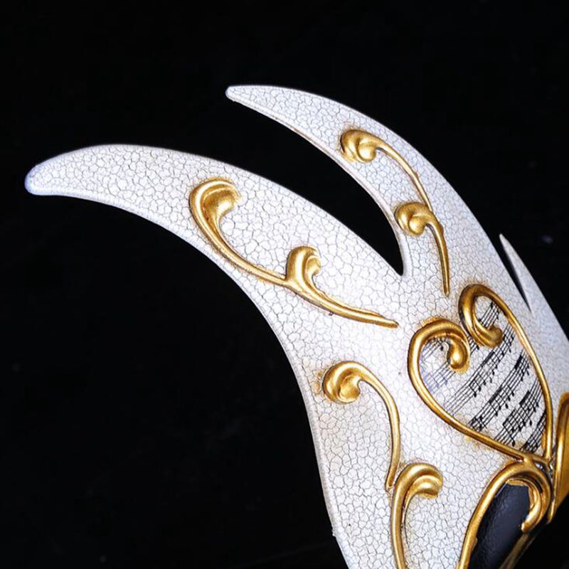 Détail du masque vénitien flamme blanc craquelé avec décorations dorées en volutes et partition musicale