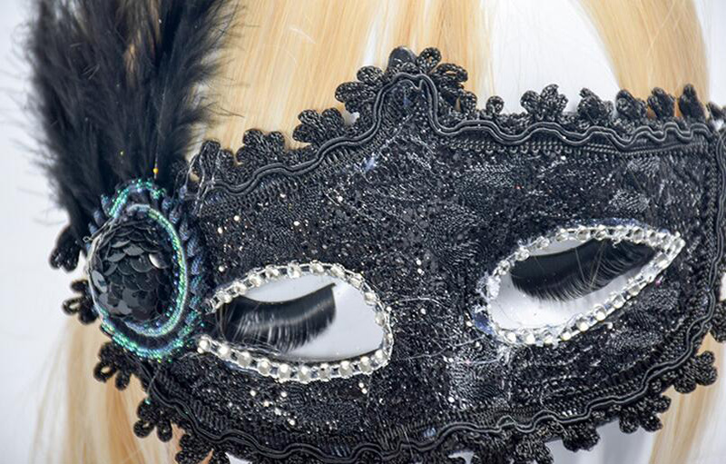 Masque vénitien noir en dentelle avec strass et plume noire sur le côté, détail décoratif circulaire
